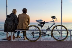 couple sitting on bench by water with parked bicycle